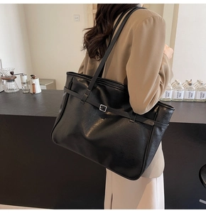 Detail of black faux leather tote bag with lychee texture and silver buckle accents