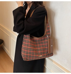 Detail of red and black houndstooth hobo bag with brown leather strap and mini pouch charm