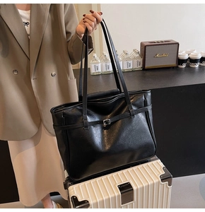 Detailed view of black PU leather tote bag with decorative buckle strap and texture