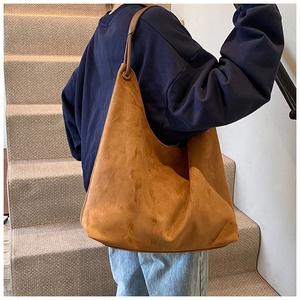 Détail d'un grand sac hobo marron en daim avec bandoulière en cuir et œillet métallique