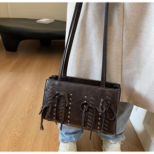 Detail of dark brown PU leather shoulder bag featuring silver rivets and woven leather laces