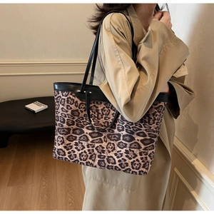 Détail du sac cabas léopard avec bordure en cuir noir porté à l'épaule du mannequin