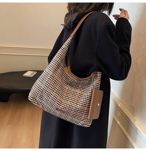 Detail of multi-color houndstooth tote bag with brown leather handles and small coin purse