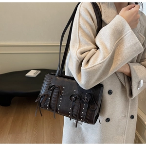 Close-up of a brown PU leather handbag with elegant pleats and decorative bow details