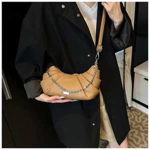 Detail of caramel pleated crescent bag featuring lychee texture and silver chain strap