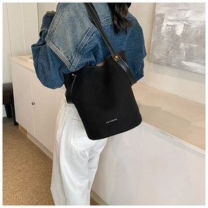 Détail du sac seau noir mat avec rivets dorés et logo blanc sur un mannequin