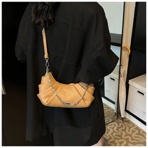 Detailed view of ginger yellow pleated dumpling bag with leather strap and silver chain