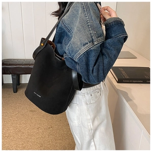 Détail du sac seau noir mat minimaliste avec ferrures dorées et texte de la marque