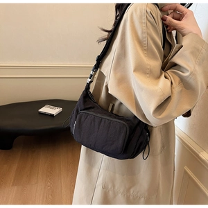 Dettaglio della borsa a tracolla in nylon nero con trama a pieghe e fibbia in metallo argento