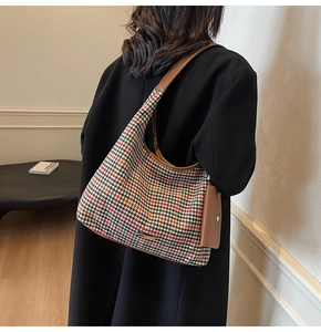 Detail of autumn houndstooth wool shoulder bag with brown leather trim and mini purse