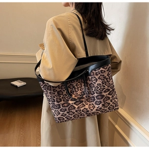 Gros plan d'un sac cabas imprimé léopard porté par un mannequin en trench-coat chic