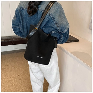 Détail d'un sac à bandoulière minimaliste en cuir PU noir mat porté par un mannequin
