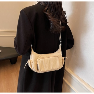 Dettaglio della borsa a tracolla in nylon beige con coulisse laterale e tasca con zip