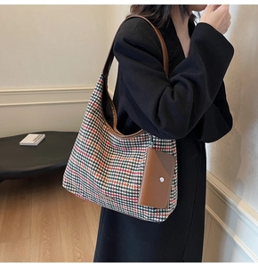 Detail of wool tote bag with houndstooth pattern and brown leather straps on shoulder