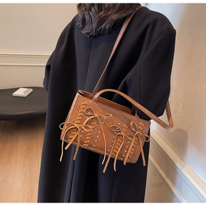Detail of vintage brown PU leather handbag featuring woven cord and bow accents on black coat