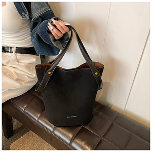 Détail du sac seau noir mat minimaliste avec clous dorés et lettrage de marque blanc
