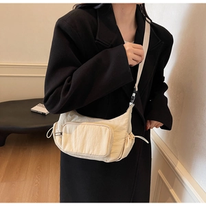 Dettaglio della borsa a tracolla in nylon crema con coulisse e tasca con cerniera