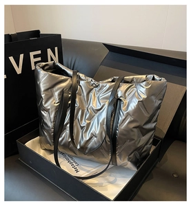 Détail du sac cabas matelassé argenté avec anses en cuir dans un coffret cadeau de luxe