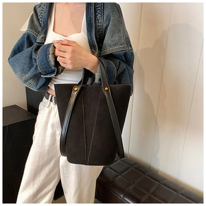 Détail d'un sac seau noir mat en PU avec des clous dorés et une bandoulière en cuir lisse