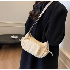 Dettaglio borsa a tracolla in nylon bianco crema con tasca con zip e coulisse