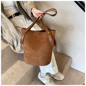 Vue détaillée du sac seau en daim marron avec des clous en métal poli et une bandoulière