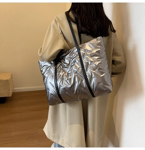Détail du sac matelassé argent métallisé avec bandoulière noire sur trench-coat clair