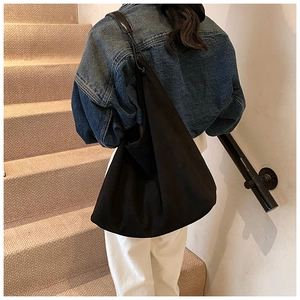 Détail d'un grand sac hobo noir avec texture mate porté dans un look de style urbain chic