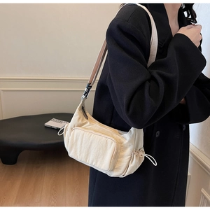 Dettaglio borsa a tracolla in nylon beige con coulisse laterali e ampia tracolla regolabile