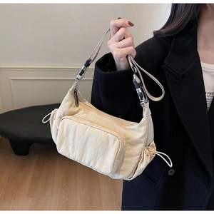 Dettaglio della borsa a tracolla in nylon beige con coulisse laterale e tasca con zip su cappotto nero