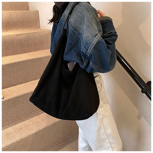 Sac à bandoulière en toile noire tendance avec silhouette souple porté par un mannequin