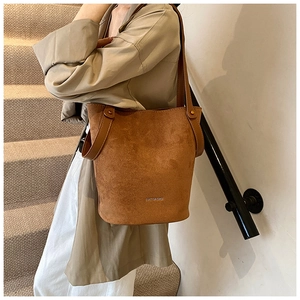 Sac seau marron texture suédine avec rivets et logo en métal porté par un mannequin