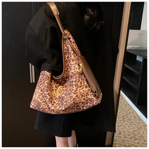 Détail d'un sac à bandoulière léopard tendance avec anses en cuir marron et zip latéral