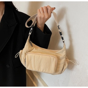 Vista laterale dettagliata di una borsa a tracolla in nylon beige con coulisse e catena argento