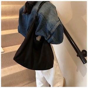 Détail d'un grand sac cabas noir mat en toile avec une structure souple et bandoulière large