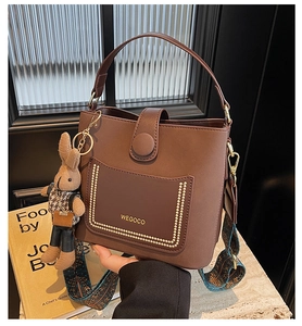 Close-up of brown bucket bag with gold studs and a stylish patterned shoulder strap