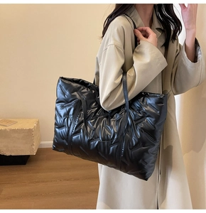 Détail du sac fourre-tout noir matelassé en tissu brillant avec fine bandoulière