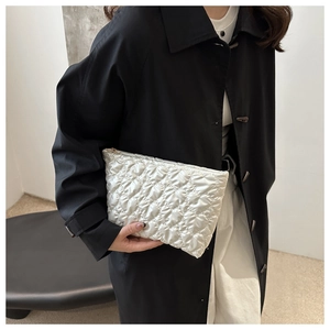 Détail du matelassage en cœur et fini métallique sur pochette chic blanche