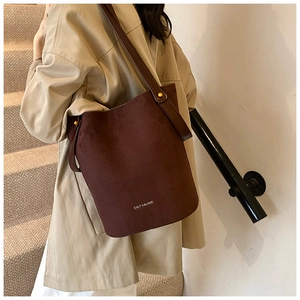 Détail du sac seau en cuir PU givré marron foncé avec rivets dorés et fine bandoulière