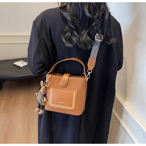 Detailed back view of caramel PU bucket bag with patterned strap and rabbit charm accessory