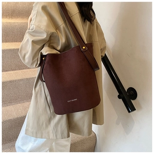 Détails de la texture du cuir PU mat et ferrures dorées sur le sac seau minimaliste