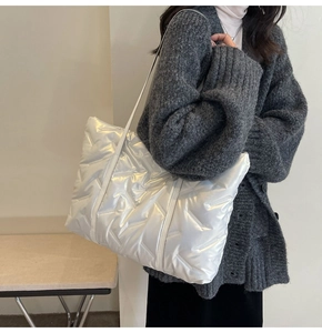Détail du grand cabas matelassé blanc brillant avec motif en V porté par le mannequin