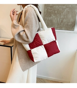 Detail of red and white checkered puffer tote bag showing quilted texture and wide strap