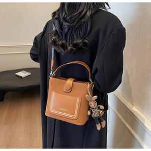 Brown PU leather bucket bag with gold logo, ethnic strap, and cute rabbit plush charm