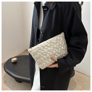 Détail d'une pochette en nylon blanc matelassé avec surpiqûres en losanges et zip