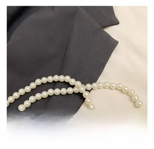 Detailed macro view of smooth white pearl handle chain for stylish autumn shoulder bag