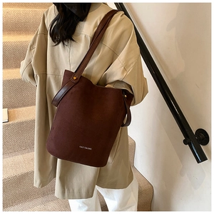 Détail d'un sac seau en cuir PU mat marron foncé avec logo de marque et fine bandoulière
