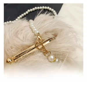 Detail of plush cream shoulder bag with faux pearl chain strap and gold metal hook