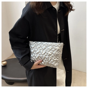 Détail du motif matelassé en cœur argenté avec finition métallique sur la pochette cosmétique