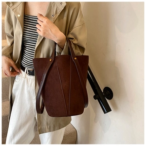 Détail du sac seau en PU mat marron foncé avec accents dorés et bandoulière en cuir