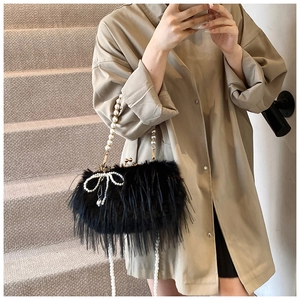 Detail view of black feather shoulder bag with pearl handle and bow on a model